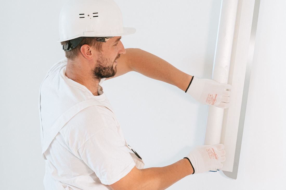 Tradesperson fits a drywall panel during interior construction.
